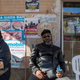 A Nigerian show promoter sits in front of posters advertising shows at a cafe in Palermo.